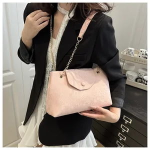 Vue détaillée du sac en cuir rose à motif serpent avec chaîne dorée sur mannequin