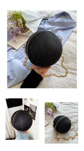 Detailed macro view of black glitter round evening bag with gold chain strap