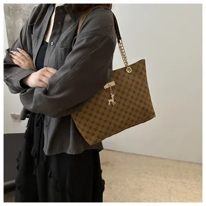 Detail of vintage brown tote bag with diamond pattern and gold deer charm pendant