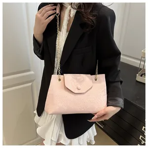 Gros plan sur la texture peau de serpent rose du sac à chaîne avec détails dorés