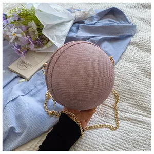 Detail of pink spherical chain bag with woven texture and gold metal chain strap