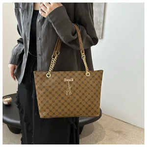 Close-up of brown printed tote bag with golden deer pendant and chain strap detail