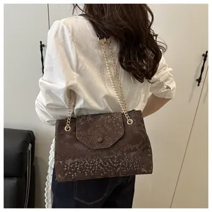 Vue arrière du modèle portant un sac à bandoulière marron foncé à motif peau de serpent