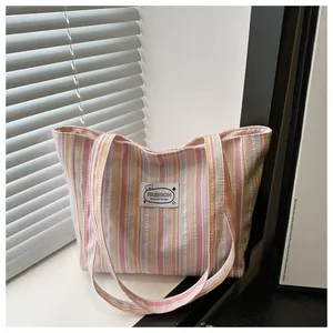 Détail d'un sac cabas en toile à rayures roses et jaunes avec étiquette de logo de mode