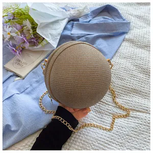 Detail of spherical straw handbag with woven texture and golden metal chain strap