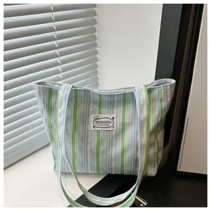 Détail du cabas en toile à rayures vertes avec écusson ours et logo brodé de mode