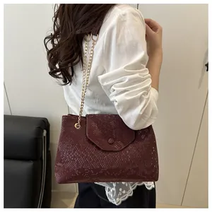Détail du sac bandoulière bordeaux aspect serpent avec chaîne dorée et boucle ronde