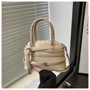 Dettaglio della borsa beige in ecopelle con fibbie decorative e tracolla regolabile