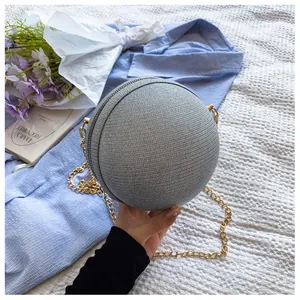 Detail of silver spherical evening bag with glitter woven texture and gold chain strap