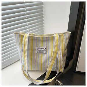 Détail d'un sac cabas en toile rayée avec des blocs de couleurs jaune, bleu et violet