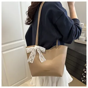 Detail of khaki tote bag with Fashion Bag text and a decorative white lace bow