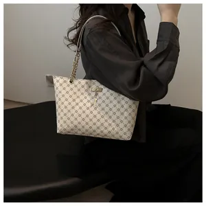 Detailed view of cream shoulder bag featuring clover pattern and gold deer charm pendant