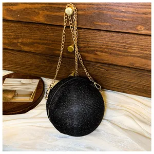 Close-up of a spherical black glitter evening bag with gold chain and zipper detail