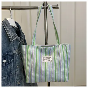 Détail d'un sac cabas en toile à rayures verticales avec étiquette mode et longues anses
