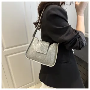 Sac sous le bras gris argenté avec texture crocodile porté par un mannequin pour la ville