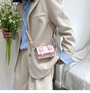 Detailed view of mini pink crossbody bag with double buckles and chunky chain on model