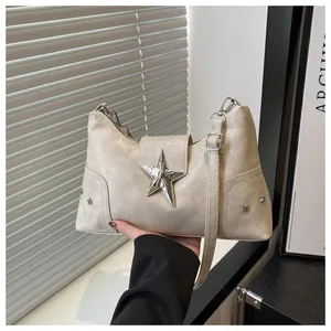 Dettaglio borsa in pelle beige con grande fibbia a stella in metallo argento e borchie
