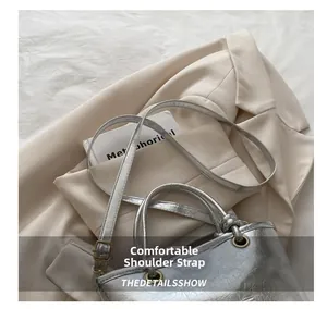 Detail of silver metallic textured bucket bag with comfortable strap on beige blazer
