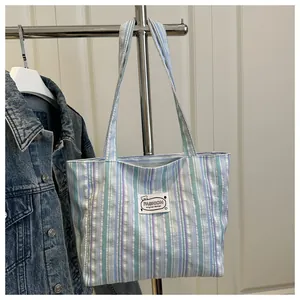 Détail du sac cabas en toile à rayures colorées montrant l'étiquette et le motif ours