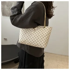 Detail of star pattern tote bag with gold giraffe charm and chain shoulder strap