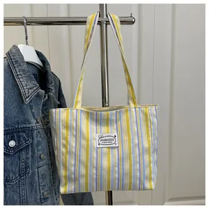 Détail d'un grand sac cabas en toile rayée avec étiquette décorative et deux bandoulières