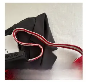 Close-up of red and white striped tote handle with lace trim on a black blazer