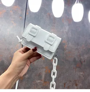 Detail of white mini Cambridge bag with chunky chain handle and buckle straps