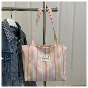 Détail du sac cabas en toile rayée colorée avec écusson ours de mode et longues bandoulières