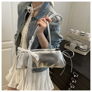 Detail of silver oil wax leather shoulder bag with white lace bow and metallic finish
