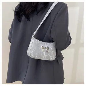 Détail du sac bandoulière argenté avec nœud métallique et texture plissée chic