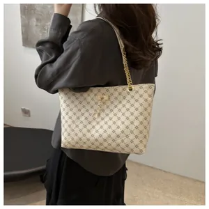 Detail of beige monogram tote bag with gold chain strap and giraffe charm pendant