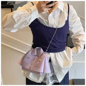 Detail of creative purple shirt-style crossbody bag with silver chain strap on model