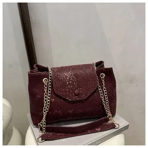 Détail de la texture serpent rouge vin et de la chaîne dorée sur le sac à rabat