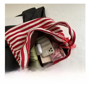 Detail showing high-capacity red and white striped tote bag with interior items