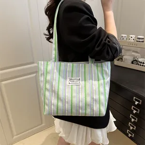 Sac fourre-tout en toile à rayures vertes et violettes porté par un mannequin en intérieur