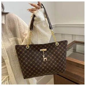 Detail of dark brown tote bag with geometric pattern, golden chain and deer charm