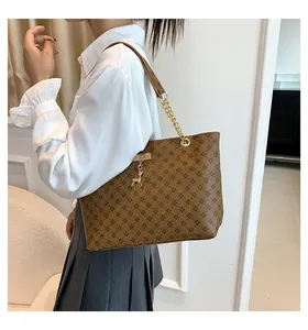 Brown tote bag with black floral pattern and gold deer charm on chain shoulder strap