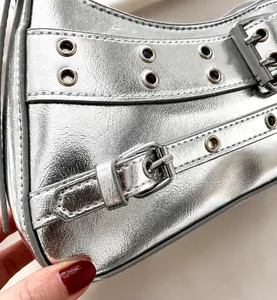 Dettaglio della pelle metallizzata argento con borchie e fibbie sulla borsa a tracolla