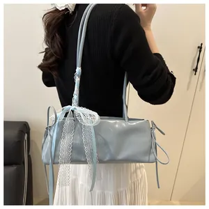 Detail of light blue oil wax leather underarm bag with a decorative lace ribbon bow