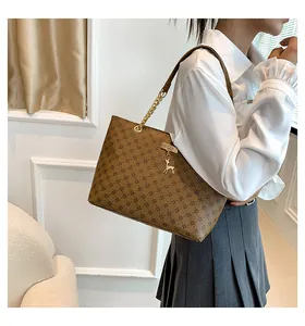 Detail of brown tote bag with geometric pattern, golden deer charm and chain strap
