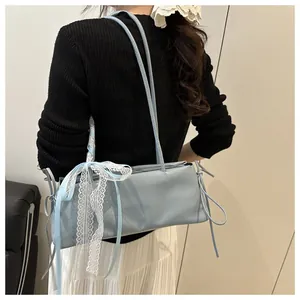 Detail of light blue oil wax leather bag featuring a white lace bow and elegant silk scarf