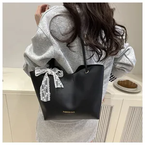 Close-up of black tote bag featuring golden lettering and a white lace bow detail
