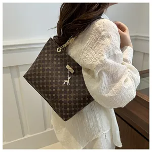 Detail of dark brown tote bag with geometric pattern, chain strap, and deer charm