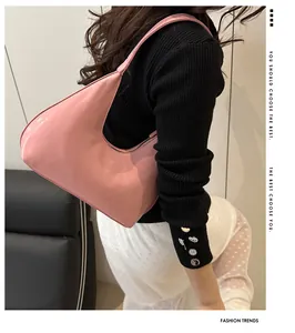 Close-up of pink crescent underarm bag with embossed fashion text on high-quality leather