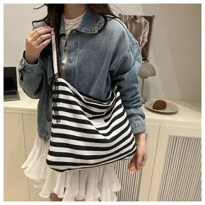 Detail of canvas tote bag featuring black and white stripes with elegant lace shoulder straps