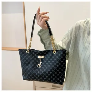 Close-up of black tote bag featuring blue grid pattern and gold deer charm pendant
