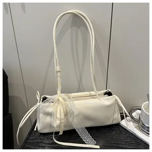 Detail of white glossy underarm bag featuring a large lace bow and long silk ribbons