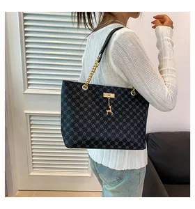 Detail of navy blue patterned tote bag with golden chain strap and deer charm on a model