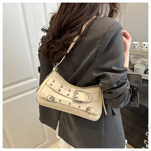 Schicke beige Y2K-Umhängetasche mit Nietösen und Schnallendetails an einem Frauenmodel