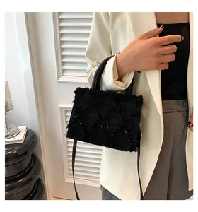 Detail of black denim tote bag with tassel diamond patterns and leather handles
